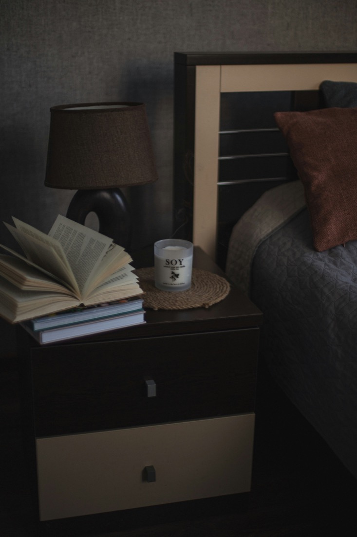 A bedside table styled with books and a candle