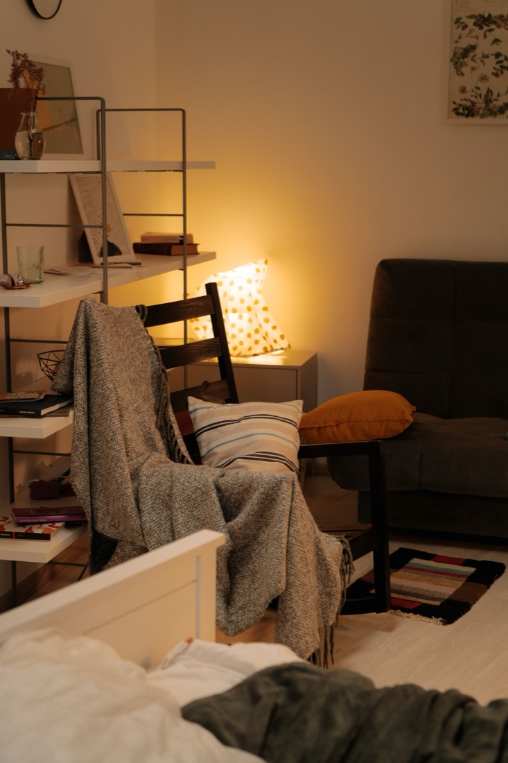 A small bedroom glowing with a single warm lamp