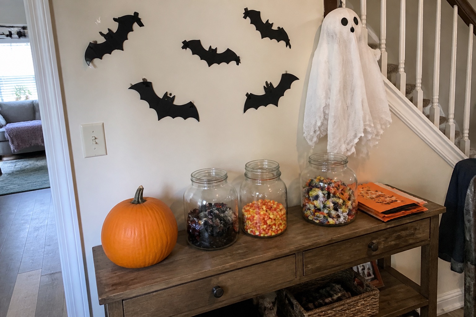 A Halloween candy apothecary with glass jars, black scoops, paper bats and amber lights