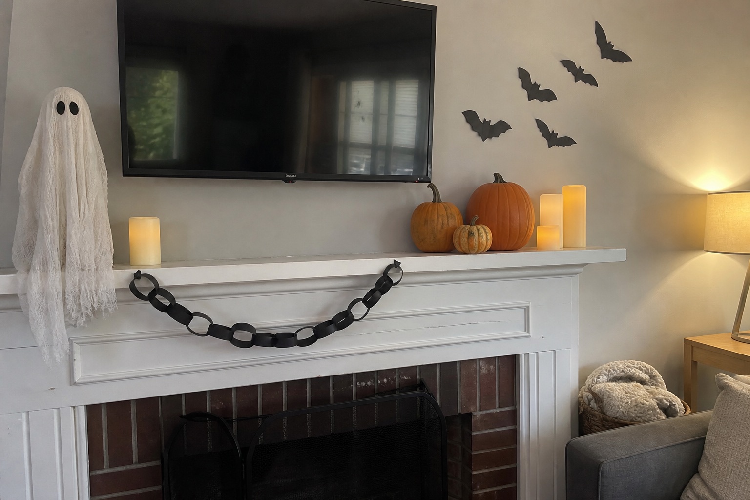 A Halloween fireplace mantel layered with ghost figures, vintage portraits, candles and dark vines
