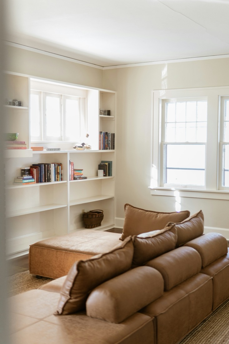 A warm neutral living room with a full bookshelf